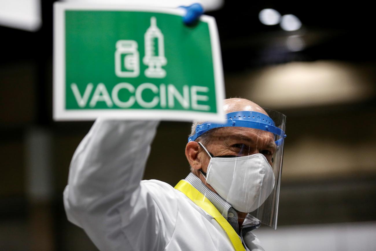 holds up a sign to signal his station needs more vaccine doses in a coronavirus disease (COVID-19) vaccination site at Lumen Field Event Center in Seattle, Washington, U.S. March 13, 2021.