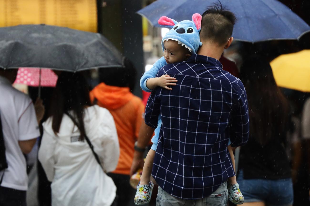  A parent carrying a child dressed in cartoon themed pajamas crosses a street in the rain in Singapore on January 10, 2021.