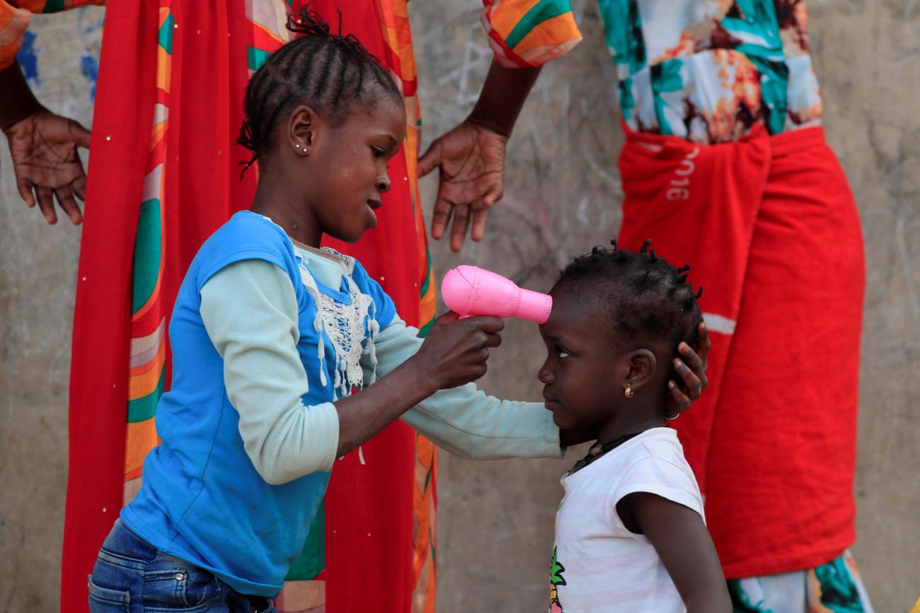 A girl uses a toy hairdryer as an infra-red thermometer on her friend as they play at Hann Bay on the eastern edge of Dakar, Senegal, April 12, 2021