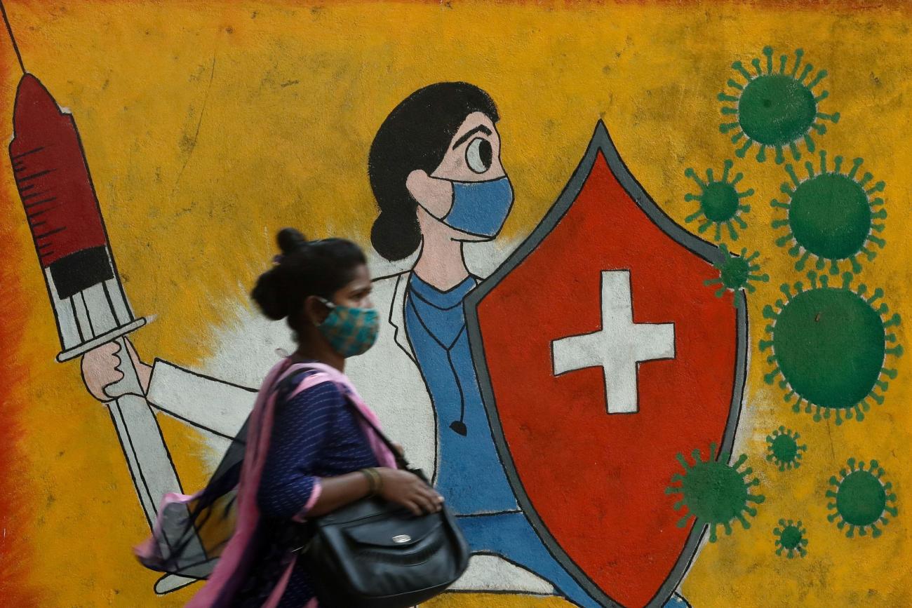 A woman walks past a graffiti on a street, amidst the spread of the coronavirus disease (COVID-19) in Mumbai, India, May 10, 2021.