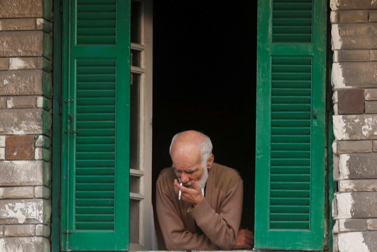 A man looks from the window of his home as he smokes a cigarette amid the coronavirus pandemic in Alexandria, Egypt on December 3, 2020.