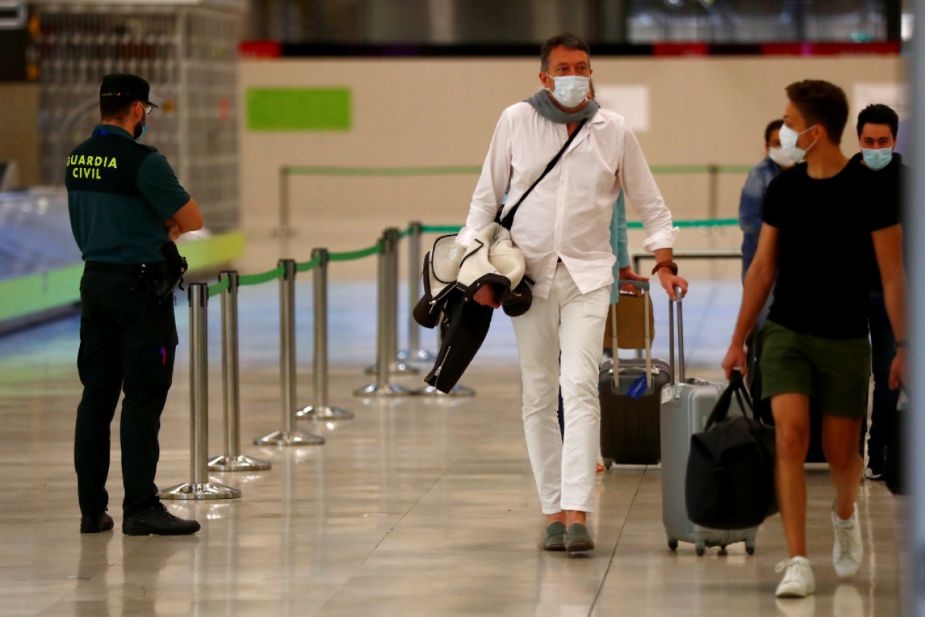 Guardia Civil officer watches as passengers, wearing protective face masks, walk upon arrival from Paris at Adolfo Suarez Barajas airport as Spain reopens June 2020