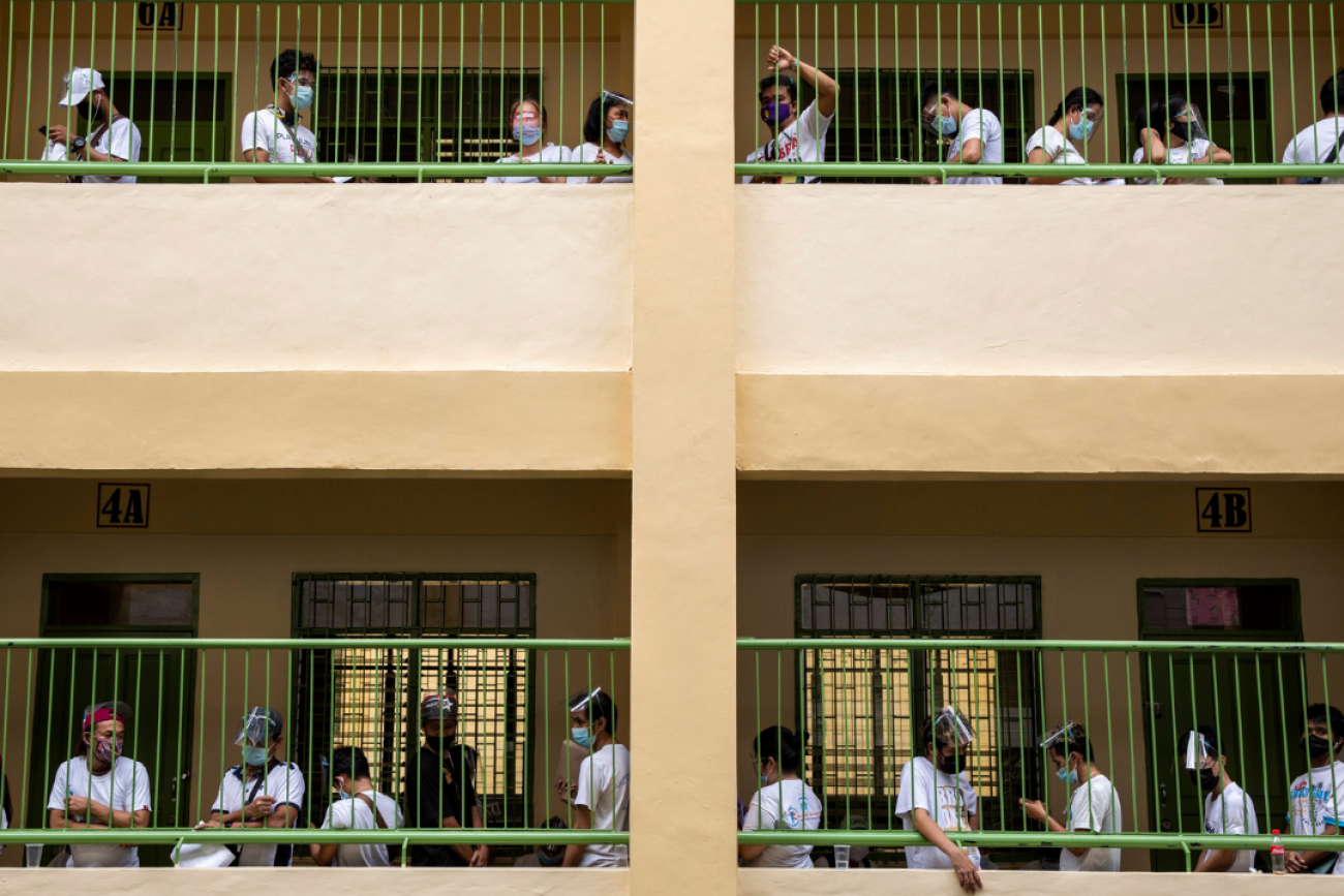 People whose jobs were affected by COVID-19 restrictions wait in lines to receive cash assistance from the government, at an elementary school in Quezon City, Metro Manila, Philippines, April 12, 2021.