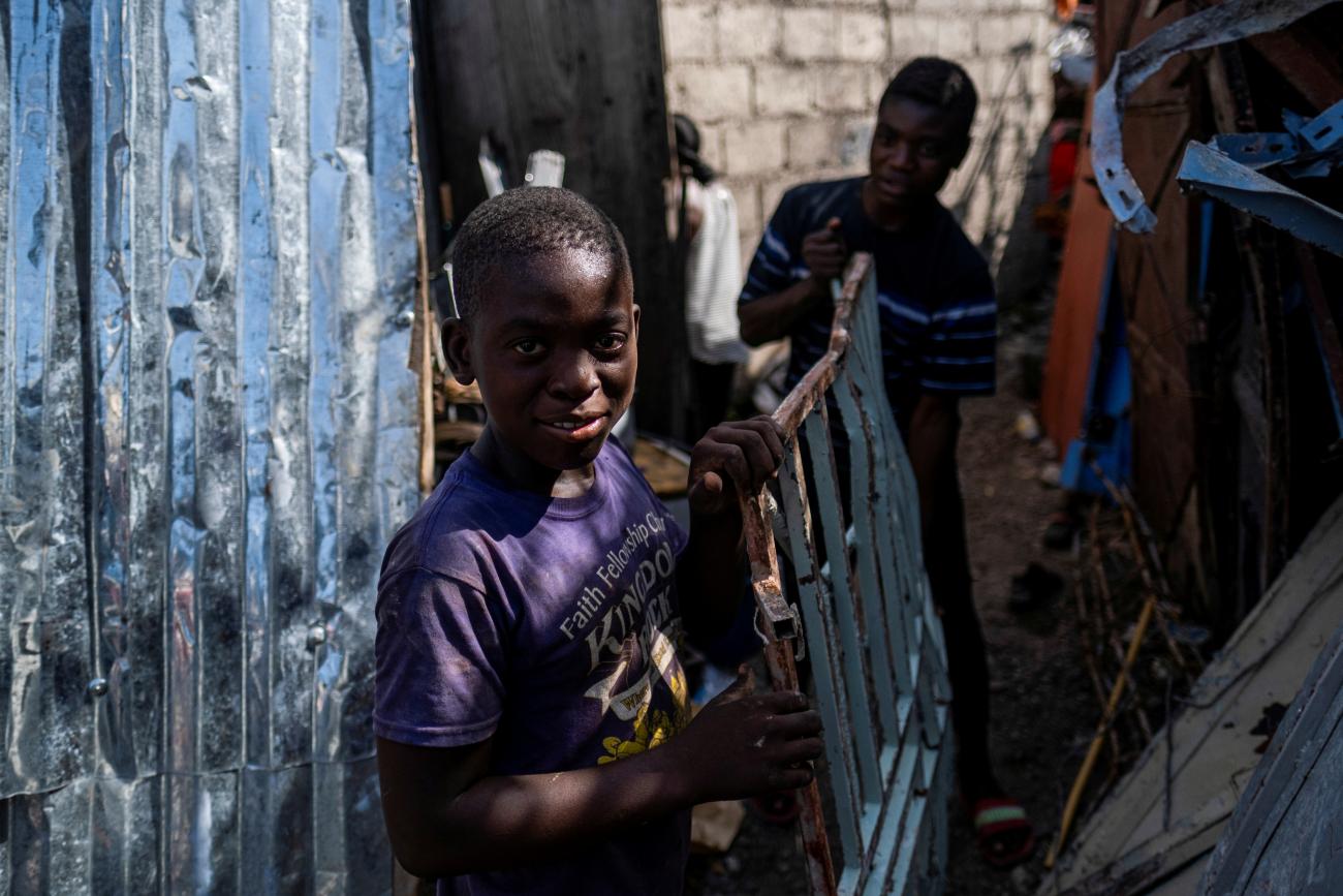 boys pick up scrap metal in the rubble of a destructed building