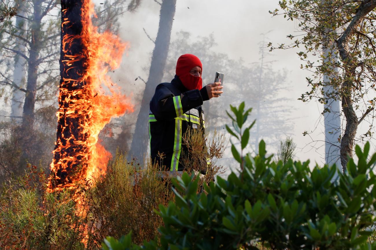 A firefighter takes a picture of a fire during a major wildfire that broke out in Vidauban, in the Var region of southern France, on August 18, 2021