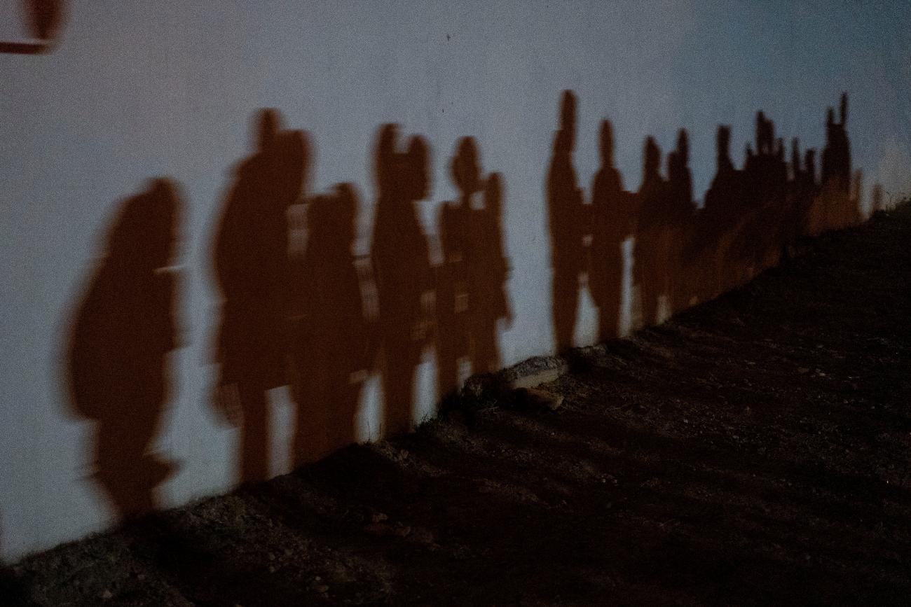 Shadows on a wall show asylum-seeking families as they queue up to be processed by the U.S. Border Patrol after crossing the Rio Grande River from Mexico, in Roma, Texas on August 12, 2021.