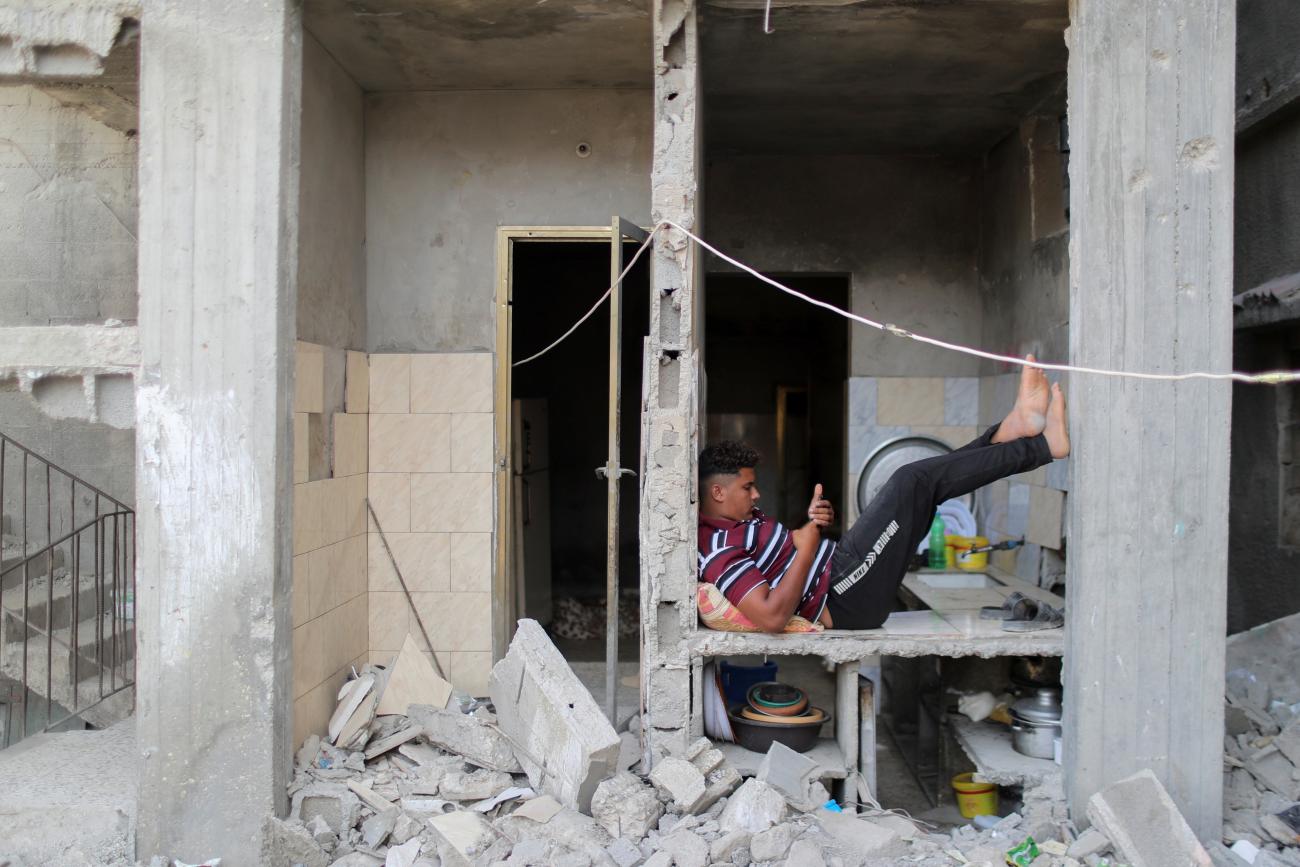  A young man uses his phone is a destroyed building