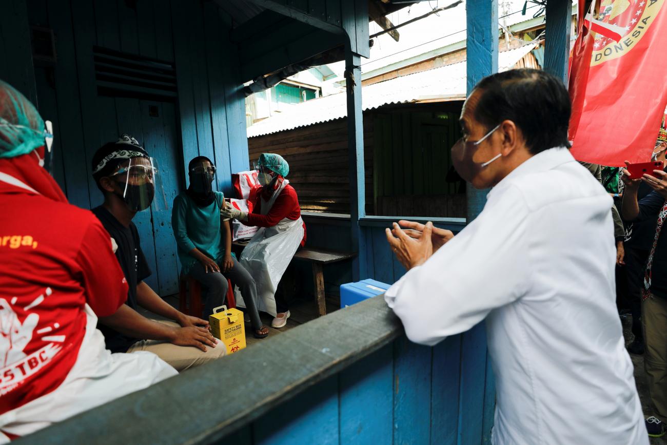 Indonesian President Joko Widodo talks with locals during a door to door mass vaccination program against coronavirus disease