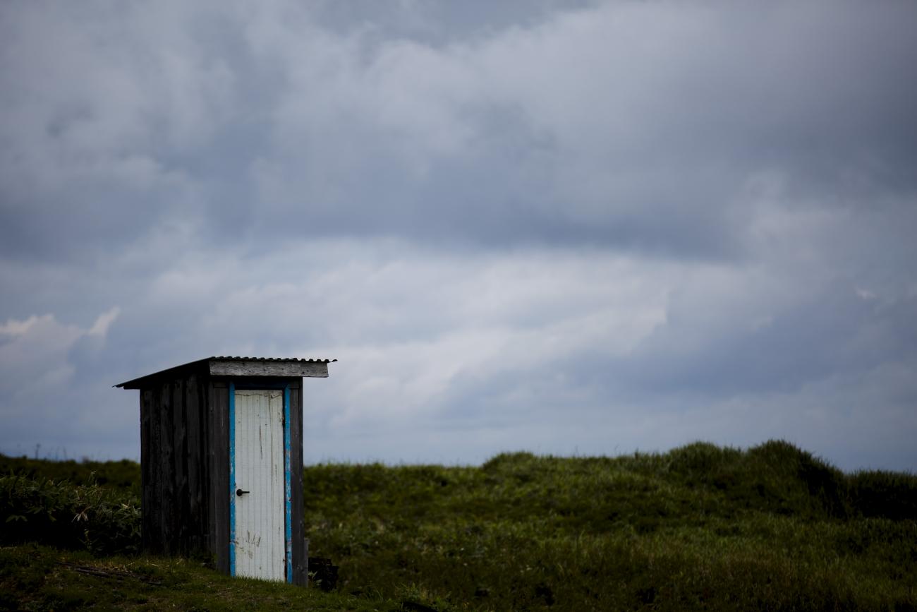 A hut is seen against a cloudy field