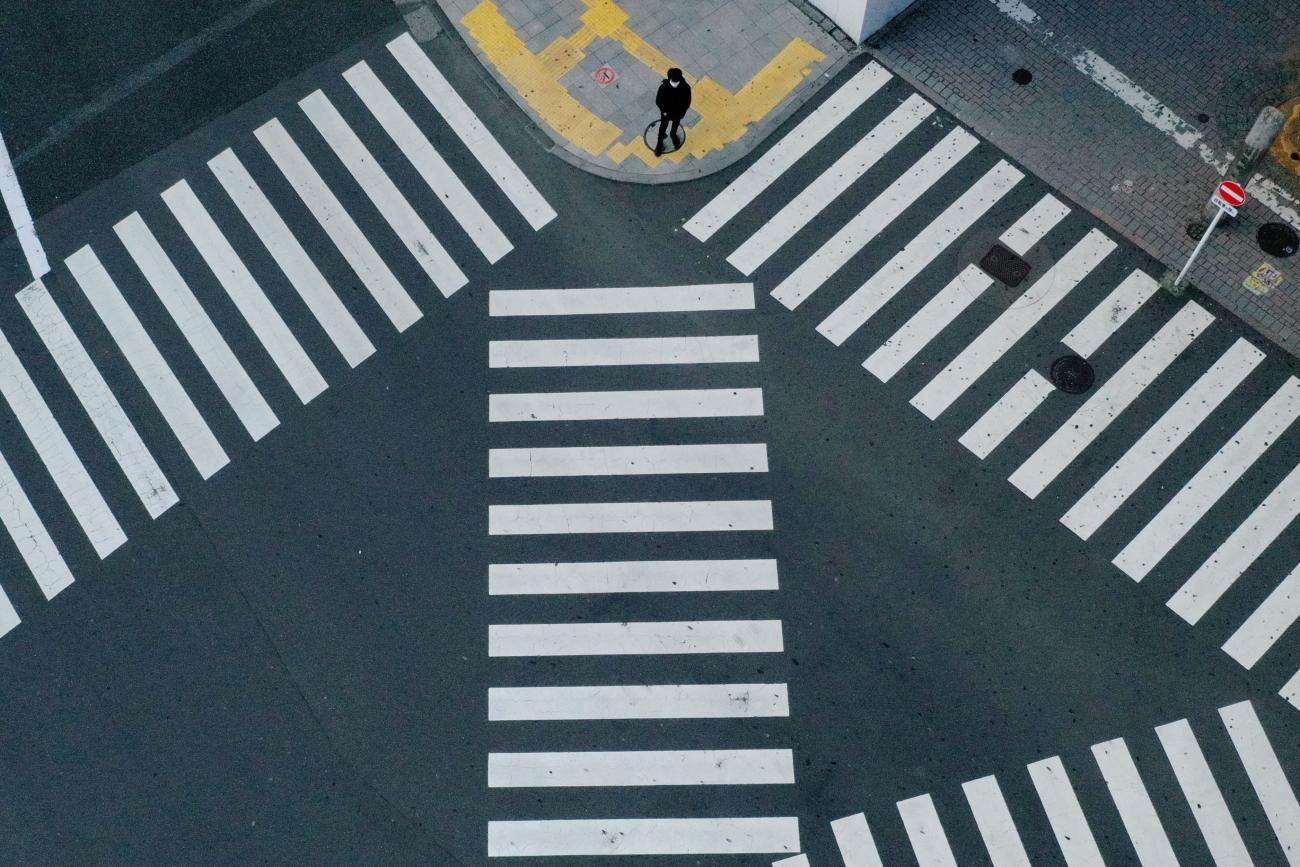A man waits to cross a street in front of Shinjuku station, a normally crowded street during the weekend, after the government expanded a state of emergency to include the entire country last week following the coronavirus disease (COVID-19) outbreak, in Tokyo, Japan, April 19, 2020