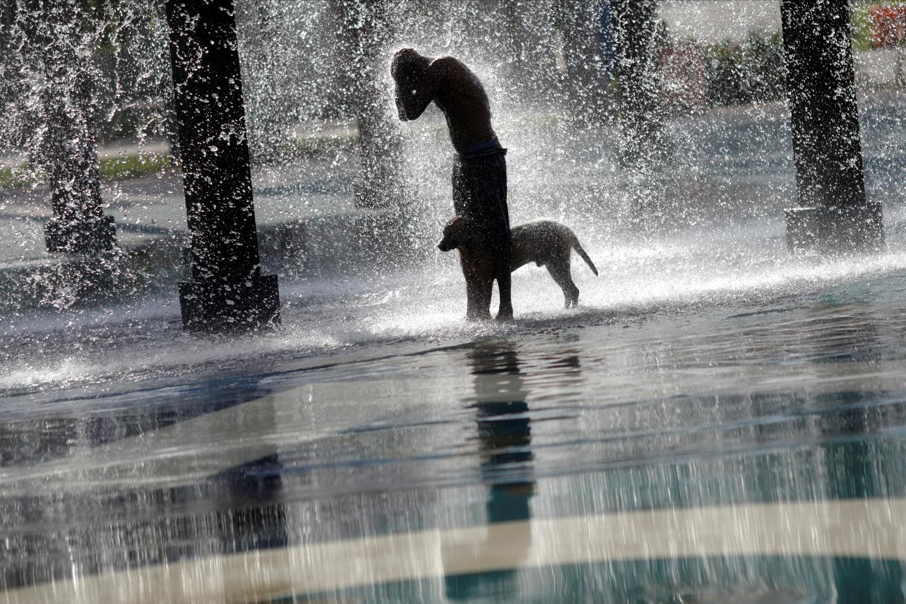 A man refreshes himself and his dog at a fountain, in Madureira Park in Rio de Janeiro, Brazil, on March 19, 2019. 