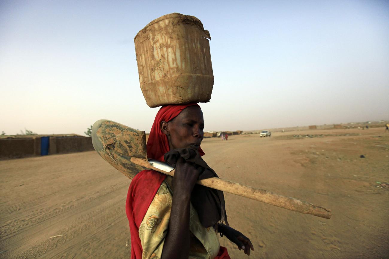  displaced Sudanese woman carries a container and shovel at the Abu Shouk IDP (internally displaced persons) camp in Al Fasher, northern Darfur April 8, 2010
