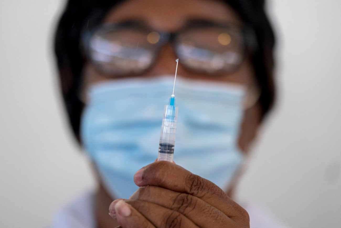 A close up image of a health worker in Haiti preparing a COVID-19 vaccine