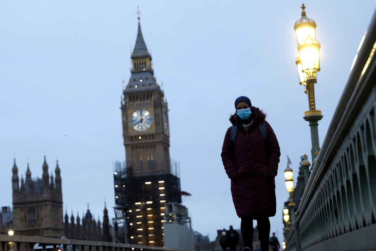 A masked pedestrian walks over Westminster Bridge in London, on January 27, 2022. 