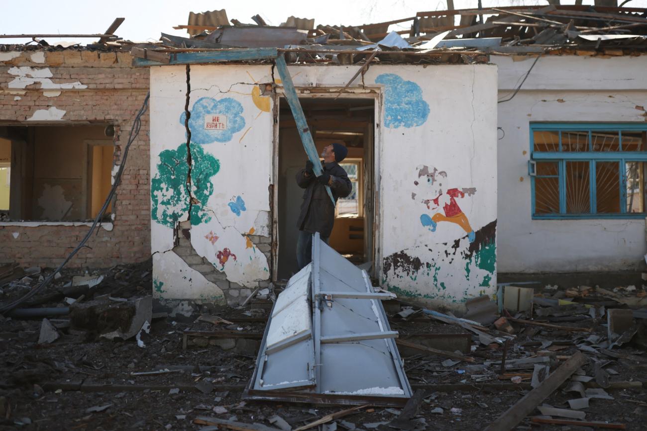A man clears rubble from a psychiatric hospital that was destroyed by Russian forces