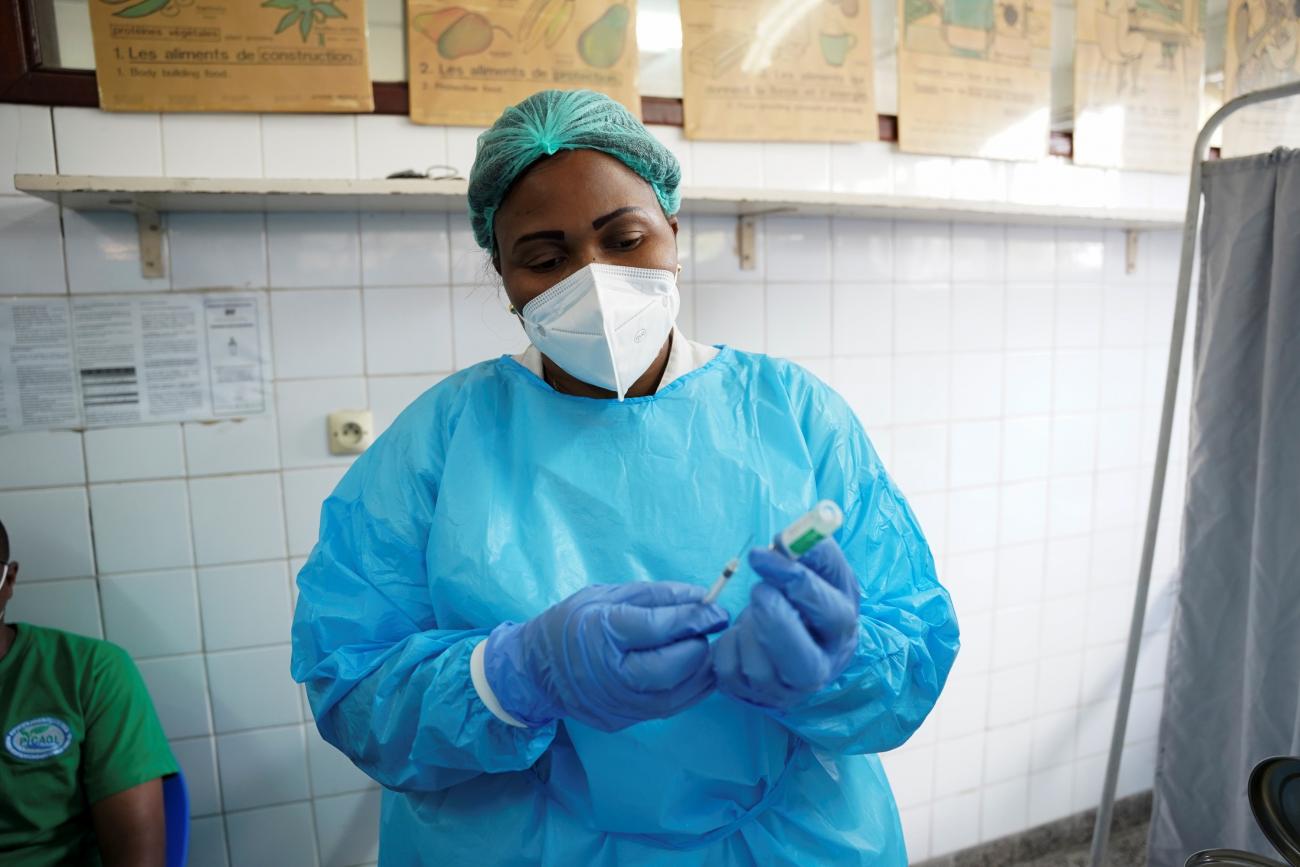 A nurse in a blue protective suit, white mask, and green hair net prepares a COVID-19 vaccine at the Ngaliema Clinic in Kinshasa, Democratic Republic of Congo, April 29, 2021.