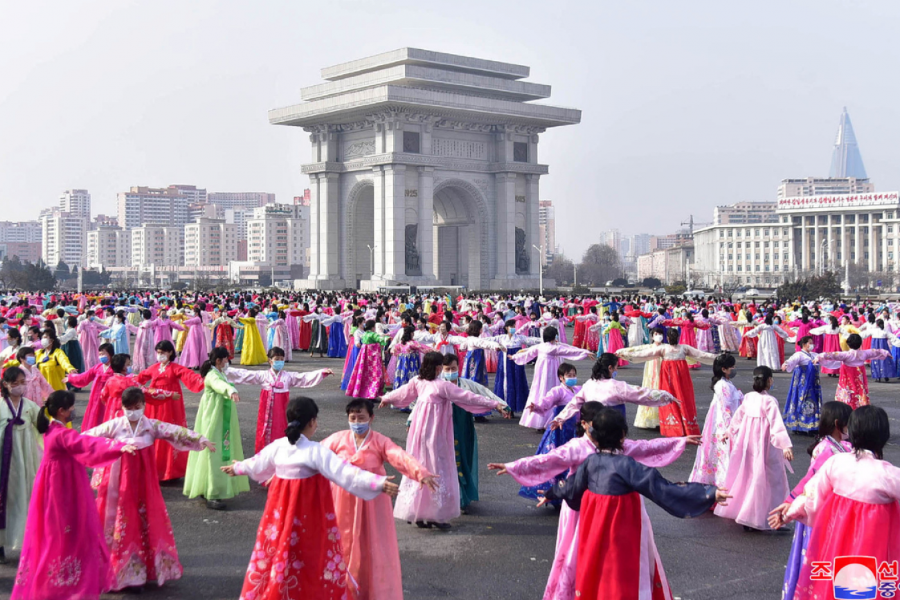 Hundreds of women dressed in pink and white traditional North Korean gowns stand in rows in a central area of Pyongyang, North Korea, on Women's Day in March 2022.