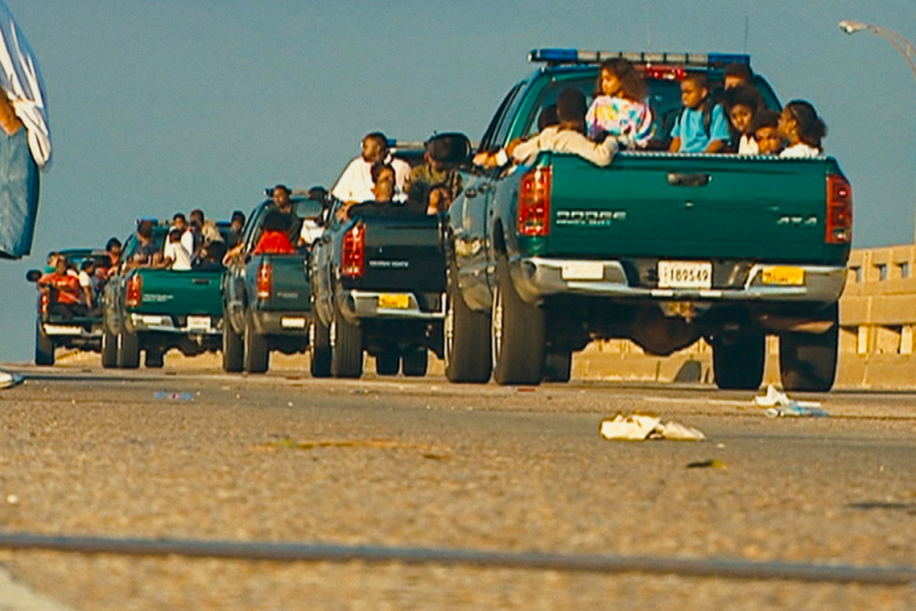 A caravan of green trucks carry child evacuees displaced during Hurricane Katrina