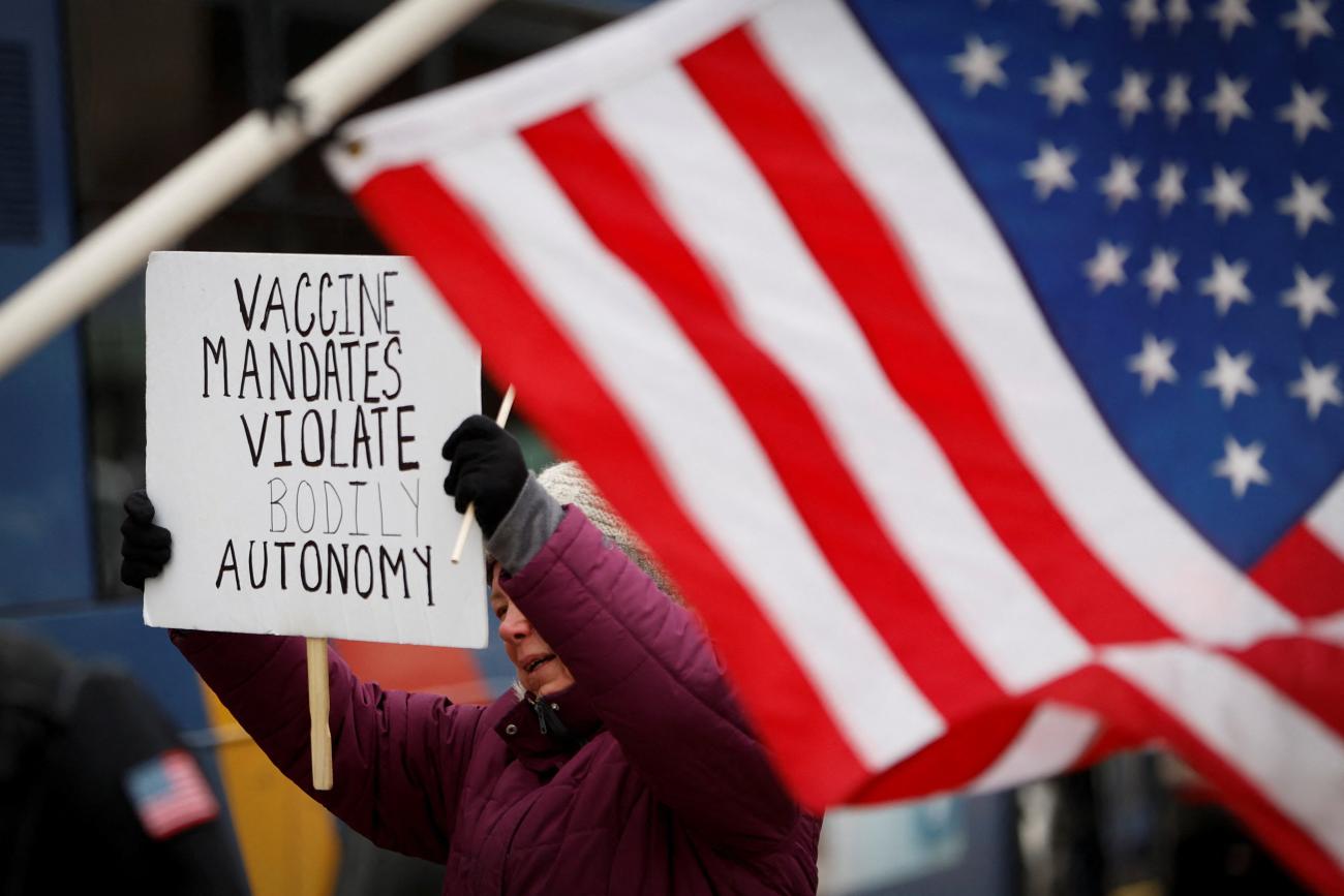 A protester holds a banner at a rally against mandates for the vaccines against the coronavirus disease (COVID-19) outside the New York State Capitol in Albany, New York.