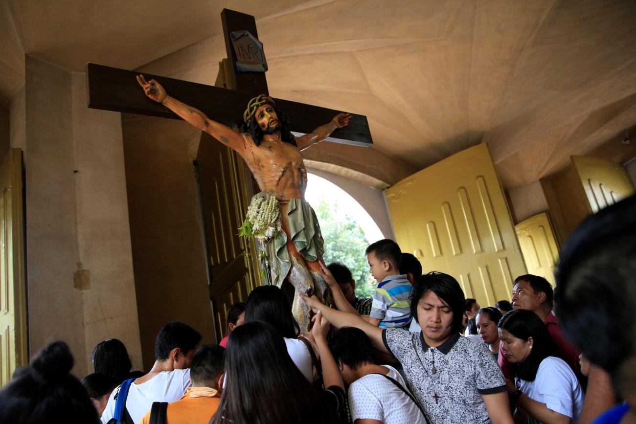 Filipino Catholic devotees touch the statue of crucified Jesus Christ after attending a mass at a National Shrine of Our Mother of Perpetual Help in Baclaran, Paranaque city, metro Manila, Philippines September 18, 2016.