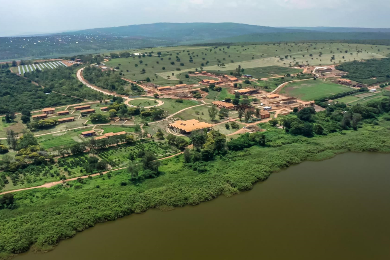 An aerial view of the green campus with earth-colored buildings alongside a river