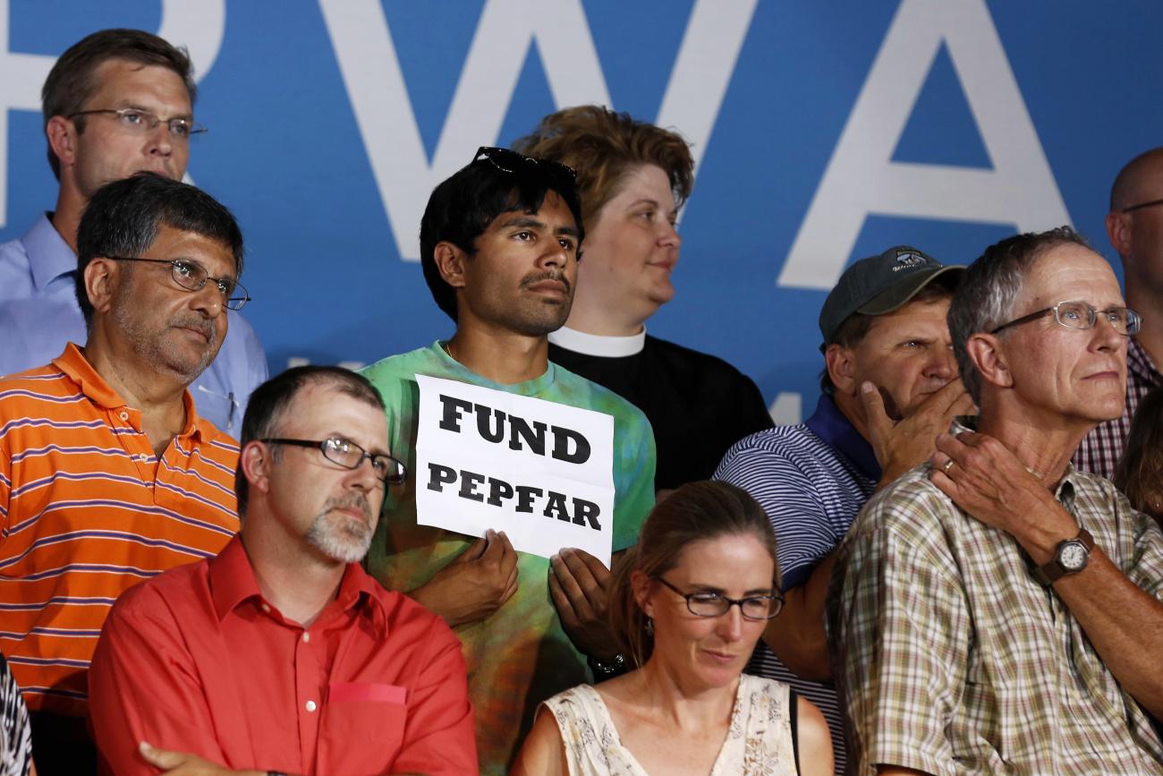 An audience member holds up a "Fund PEPFAR" sign, during President Barack Obama's speech at a campaign event at Herman Park in Boone, Iowa, on August 13, 2012. 