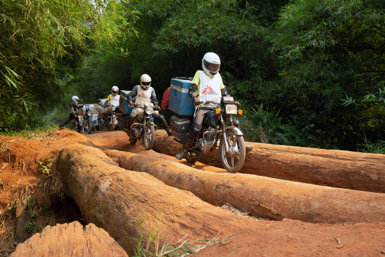 A motorcycle convoy carrying measles vaccines for the NGO Doctors Without Borders crosses a log bridge in Mongala Province, in the Democratic Republic of Congo, on February 27, 2020. 