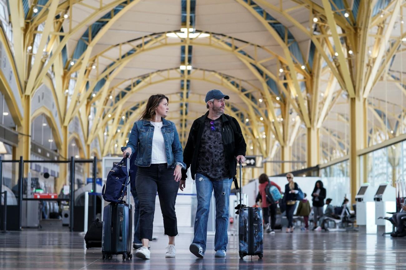 An unmasked couple makes their way through Ronald Reagan Washington National Airport after the Biden administration announced it would no longer enforce a mask mandate, on April 19, 2022. 