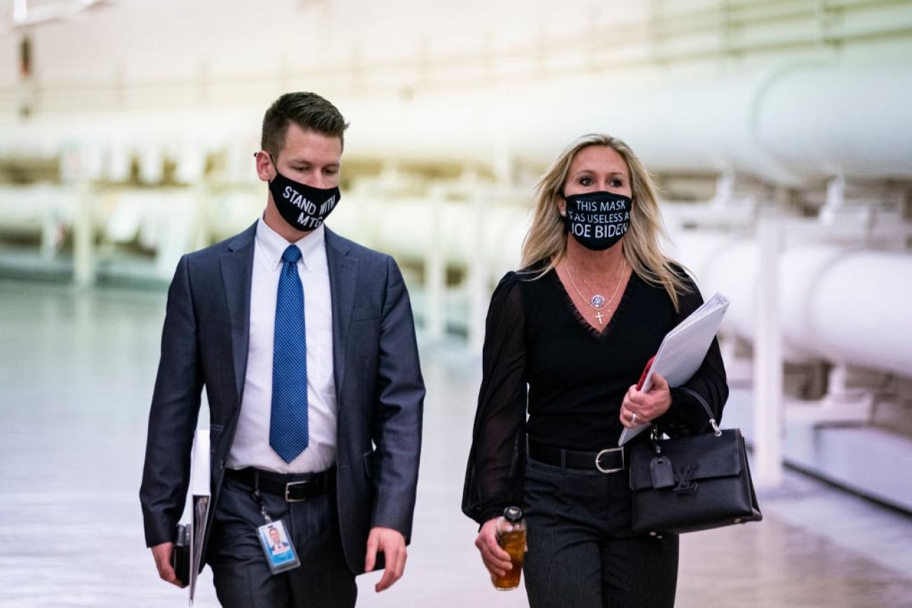 Rep. Marjorie Taylor Greene (R-GA) wears a protective mask bearing the words "This mask is as useless as Joe Biden," as she walks with an aide to a vote in the Cannon Tunnell on Capitol Hill, in Washi