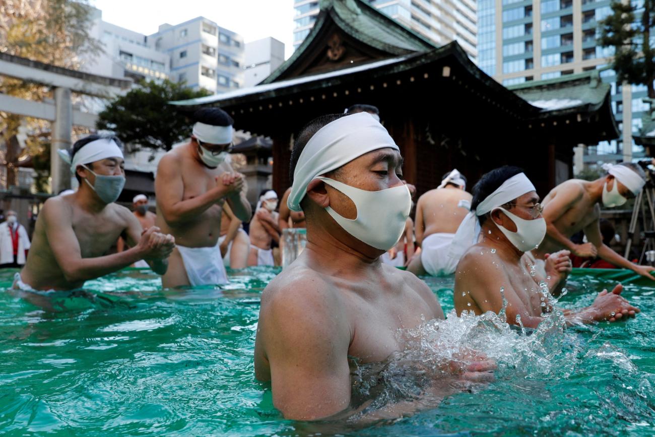 Participants wearing protective face masks amid the coronavirus disease (COVID-19) outbreak, pray as they take an ice-cold bath during a ceremony to purify their souls and to wish for overcoming the pandemic at the Teppozu Inari shrine in Tokyo, Japan, January 9, 2022.