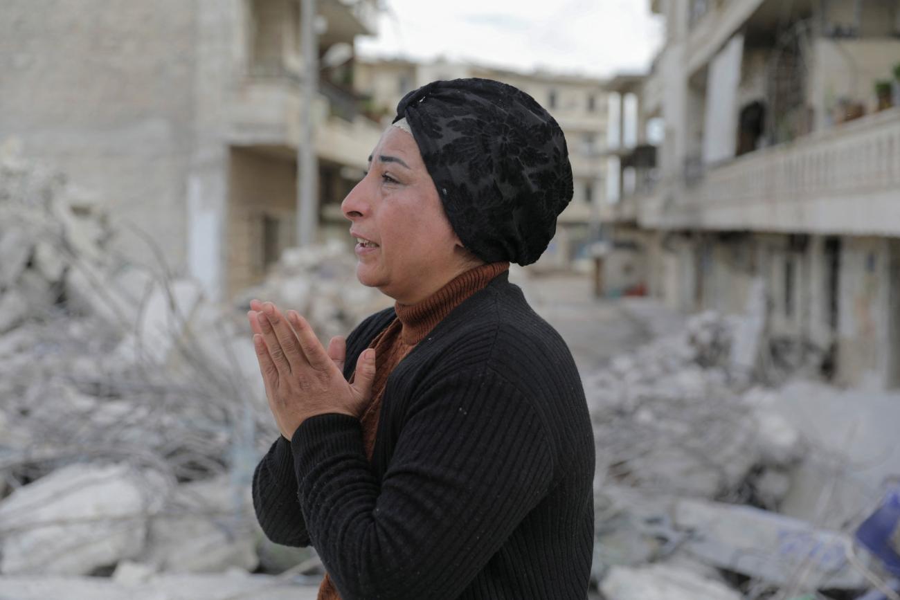 Two men stand on rubble from a building that collapsed from last month's deadly earthquake in the rebel-held town of Jandaris, Syria, on March 12, 2023. 