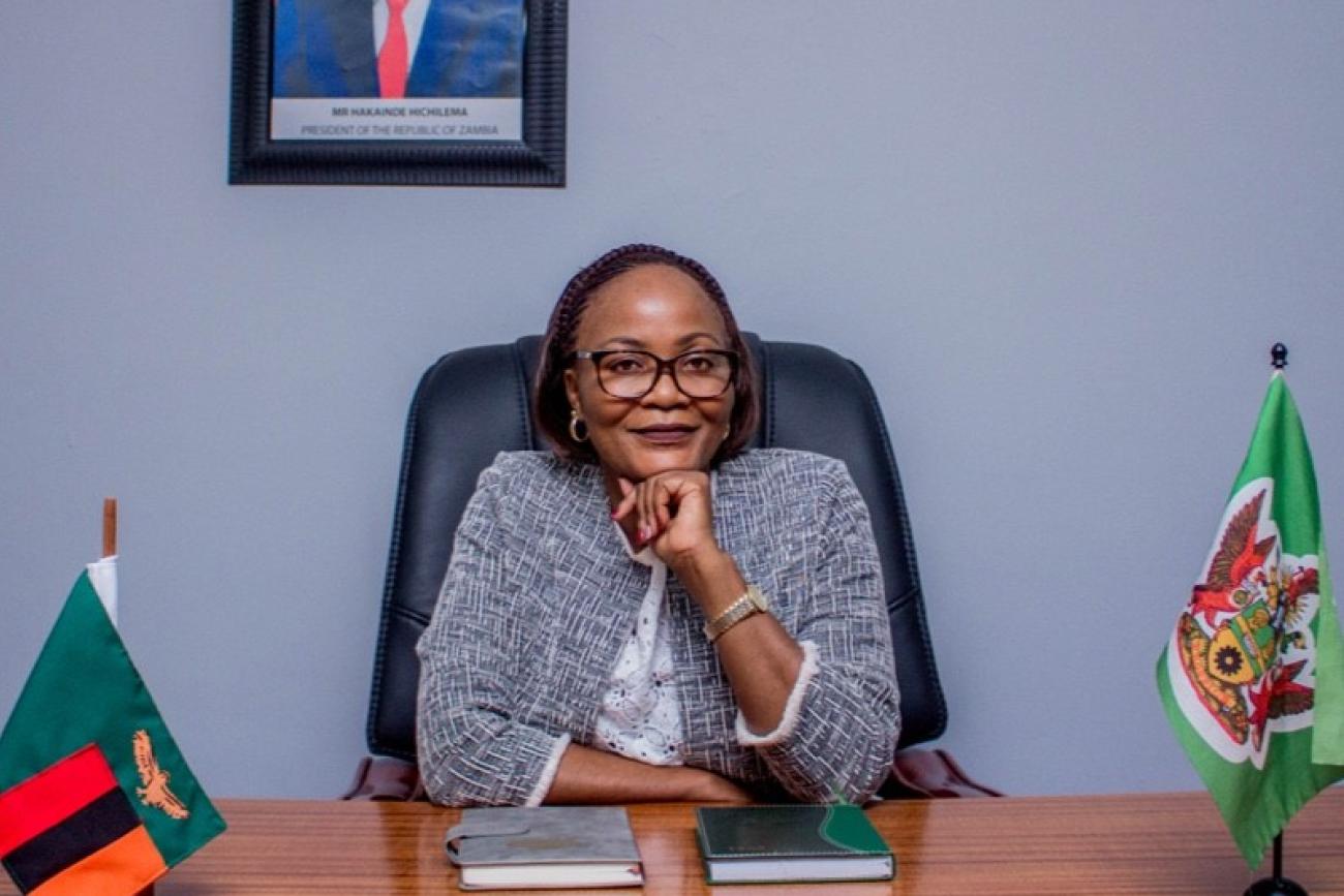 Mayor Chilando Chitangala wears a light blue tweed blazer and sitesin a black desk chair in her office