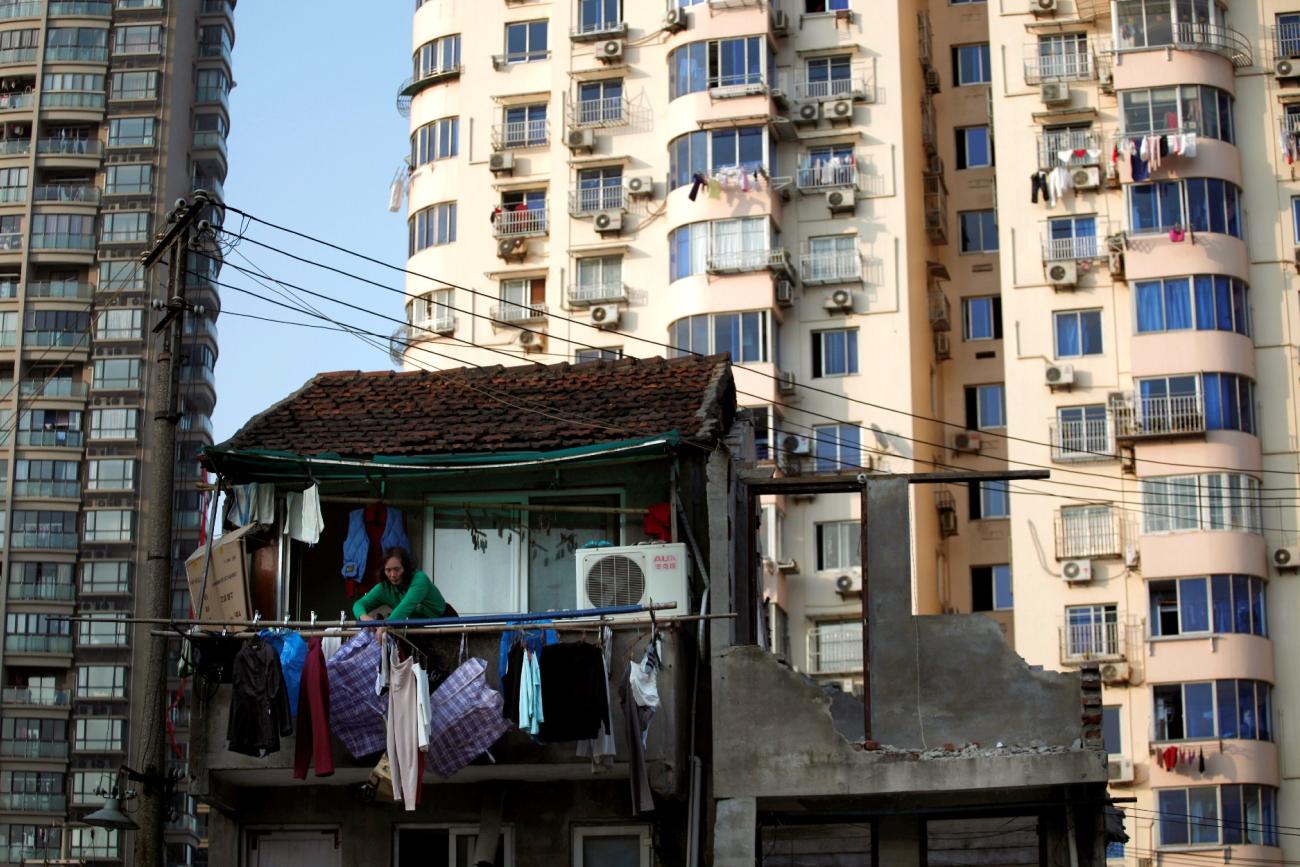 A woman stands at the balcony of her house which will be demolished to build new apartments in downtown Shanghai, China, on December 1, 2010. 