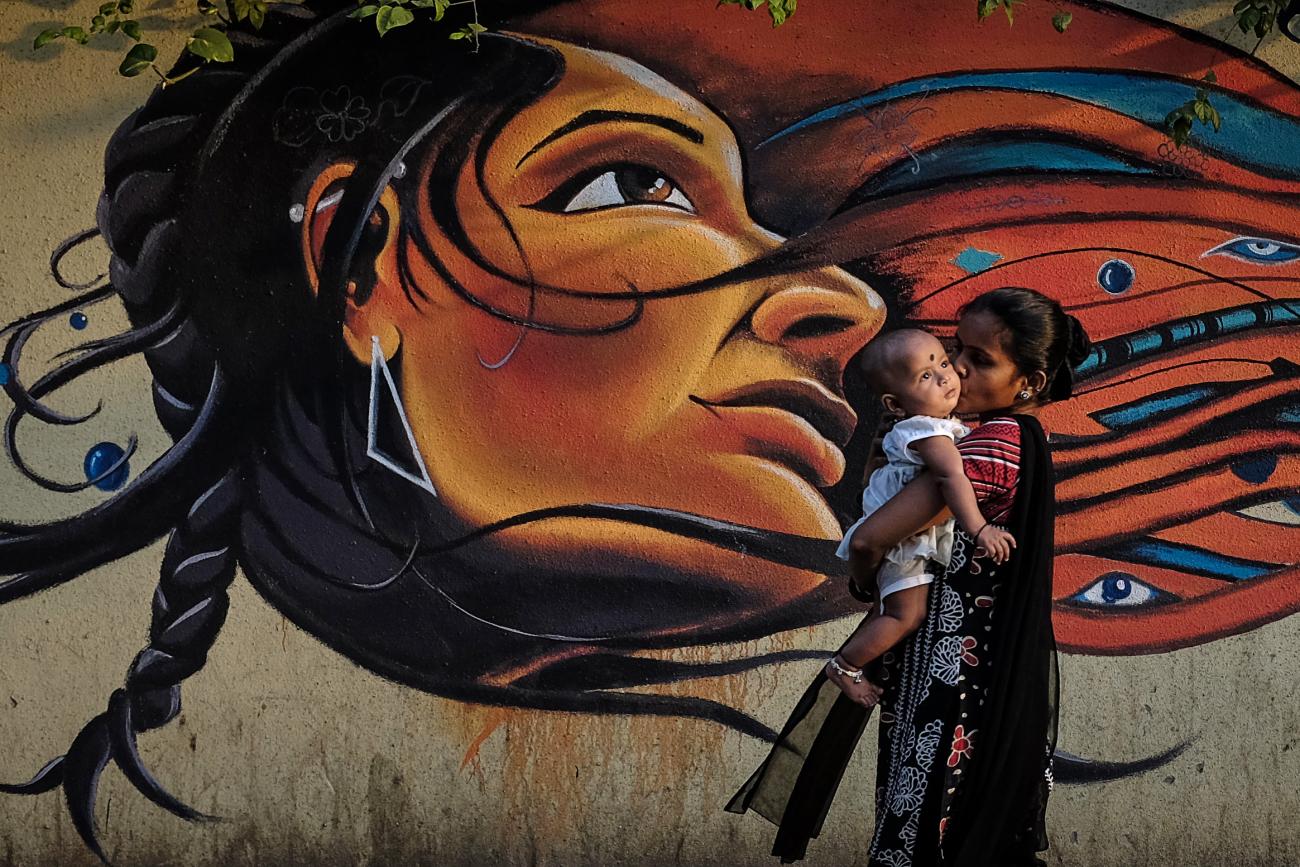 A mother kisses her child as she walks past graffiti in Mumbai March 27, 2014.