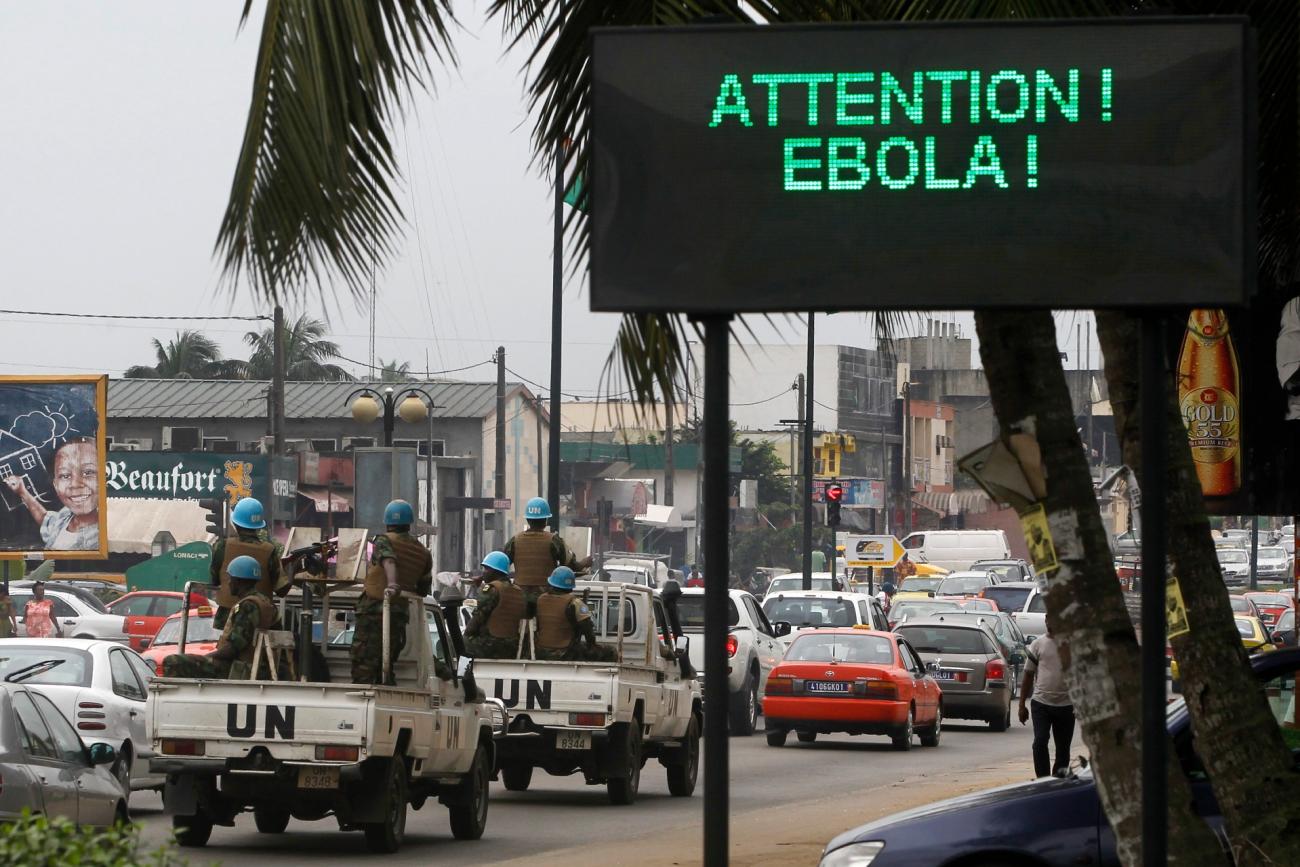 A U.N. convoy of soldiers passes a screen displaying a message on Ebola on a street in Abidjan August 14, 2014. 