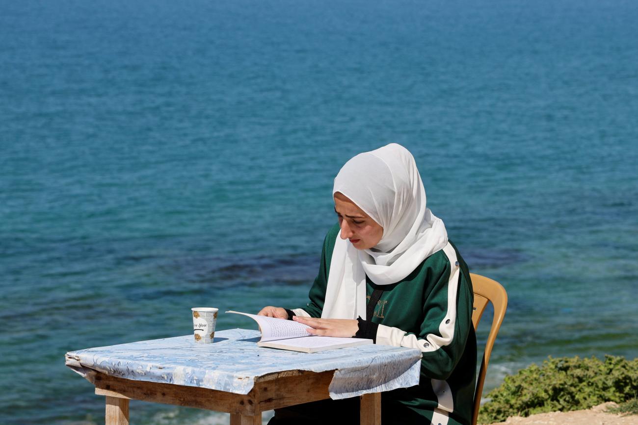 A Palestinian girl reads a book in Moumen Toman's coffee shop in Gaza Strip