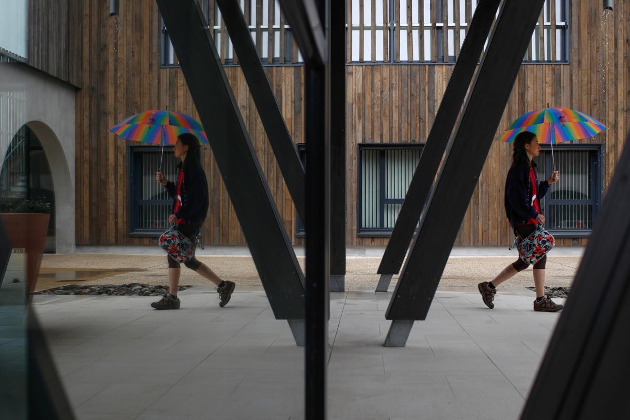 Alzheimer's patient Laetitia, 39, is reflected in a mirror as she walks with an umbrella at the Village Landais Alzheimer site in Dax, France, September 24, 2020. Picture taken on September 24, 2020.