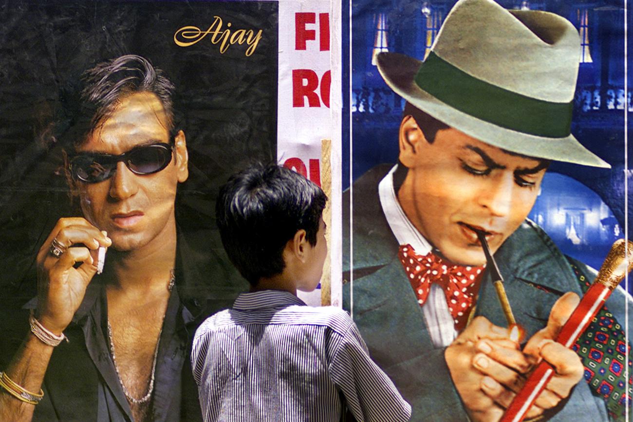 A boy looks at a posters of Bollywood stars smoking cigarettes during An anti-tobacco demonstration in Bombay, India.