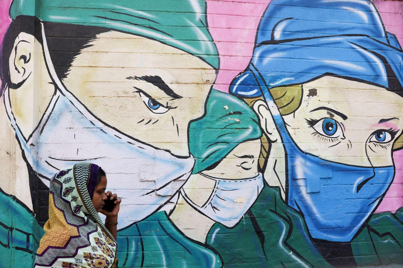 A woman walks past a coronavirus (COVID-19) themed mural on a street in Mumbai, India, March 28, 2023.