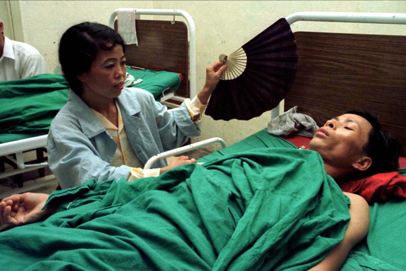 A man is fanned by his wife in the post-operative ward at Institute of Tuberculosis and Respiratory Diseases, after a lung operation for complications caused by tuberculosis, in Hanoi, Vietnam.