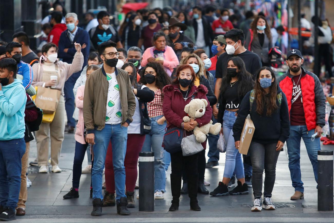 A crowd of people walk on a sidewalk.