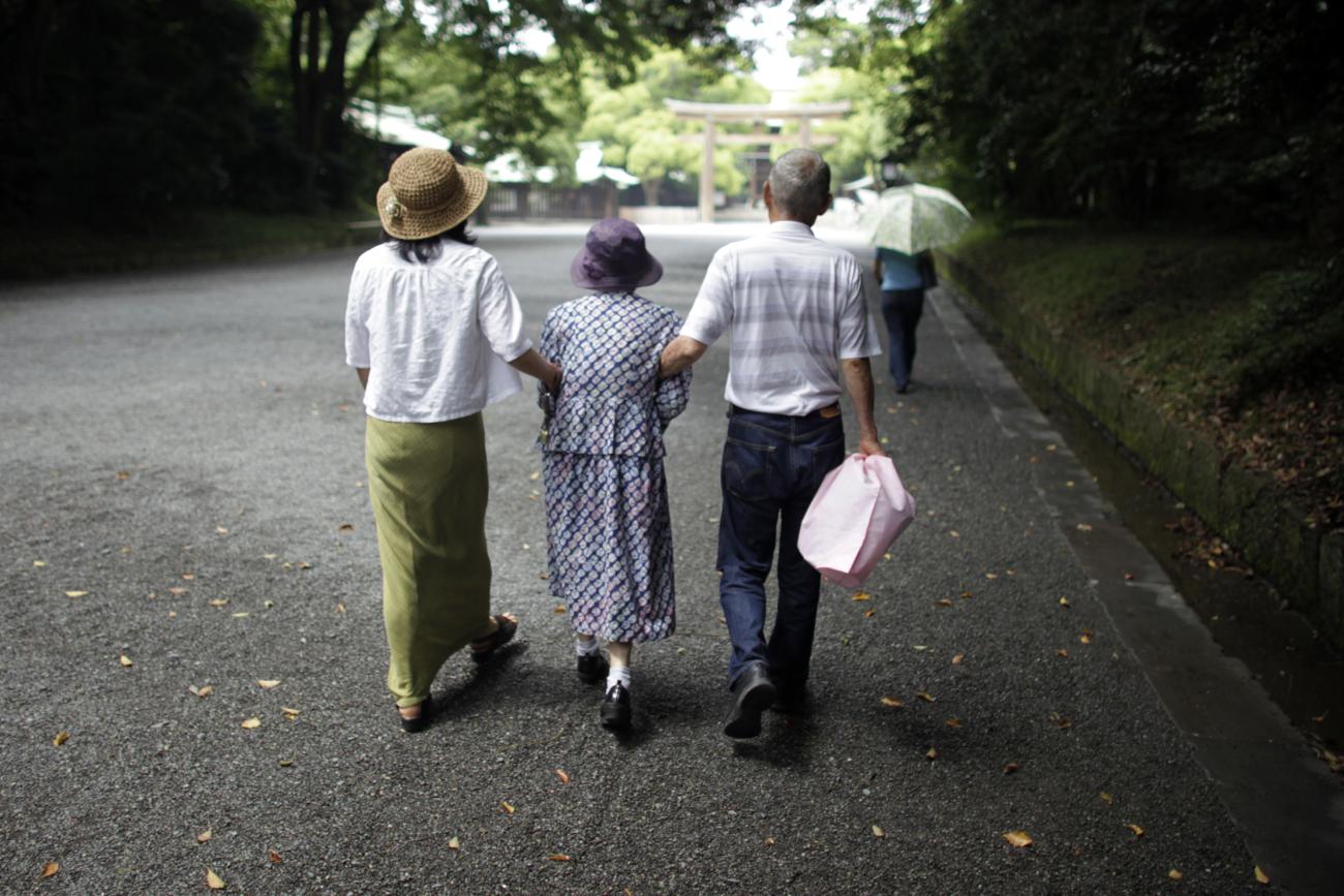 Three people walk down a street with their arms linked.