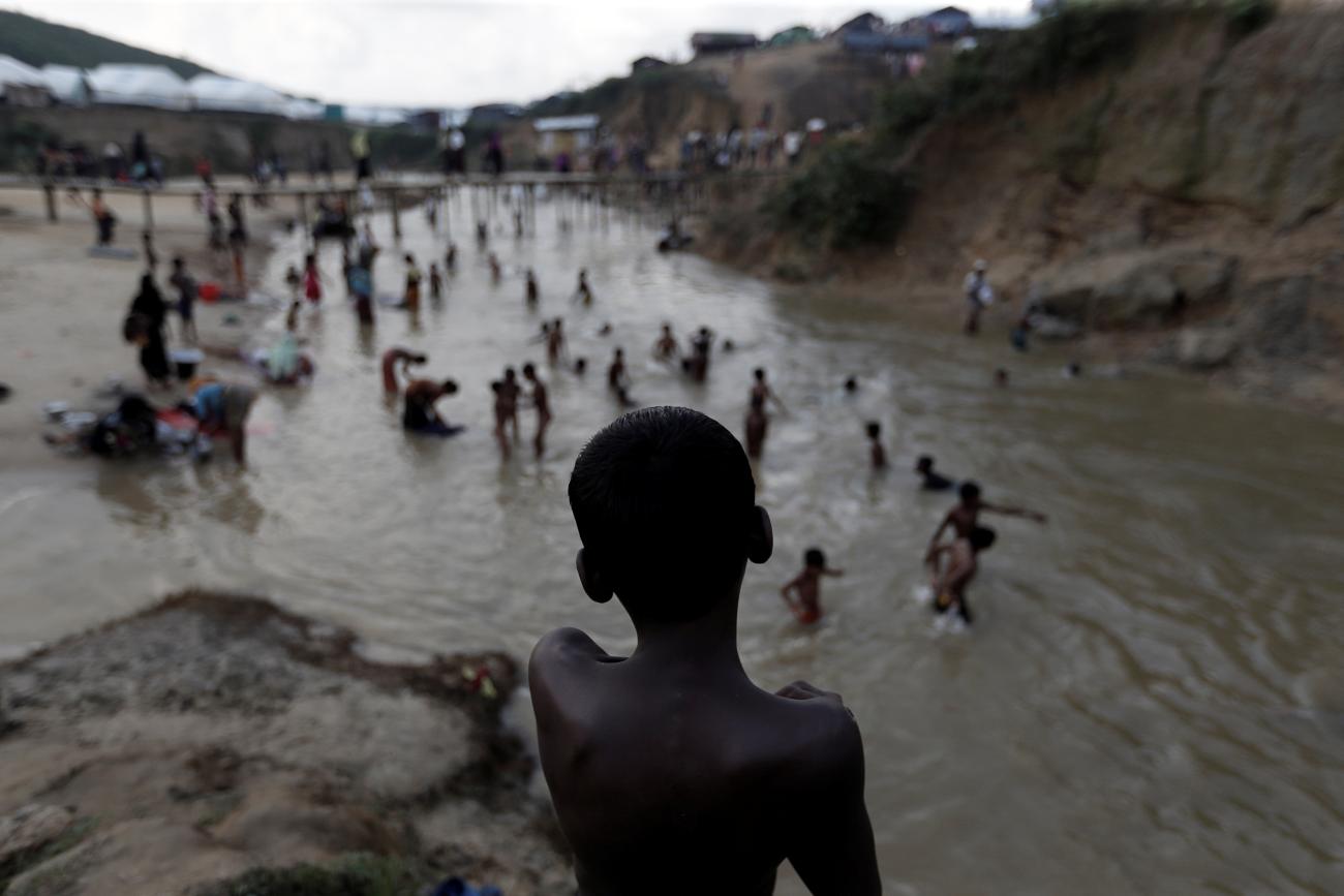 Rohingya refugees swim in a river running through a camp in Cox's Bazar