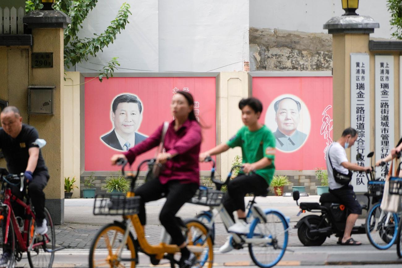 People pass by portraits of Chinese President Xi Jinping and late Chinese chairman Mao Zedong.