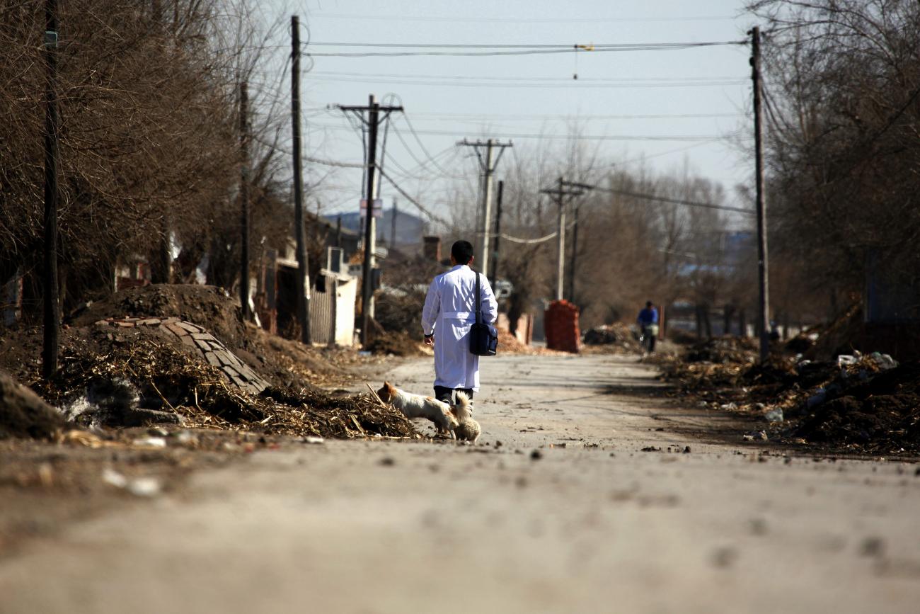 Doctor Li Tongqiang walks along a road through the village of Jianhua.