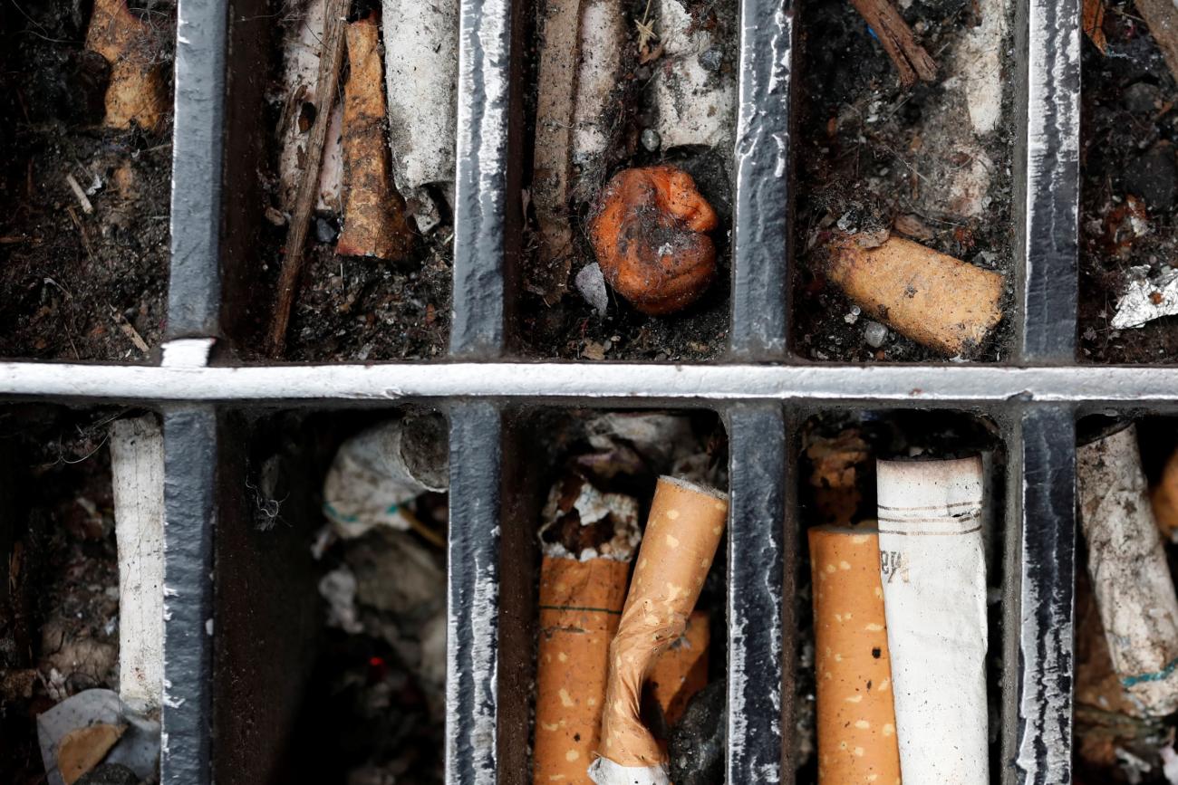 Discarded cigarette butts are seen lodged in a sidewalk grating in Manhattan.