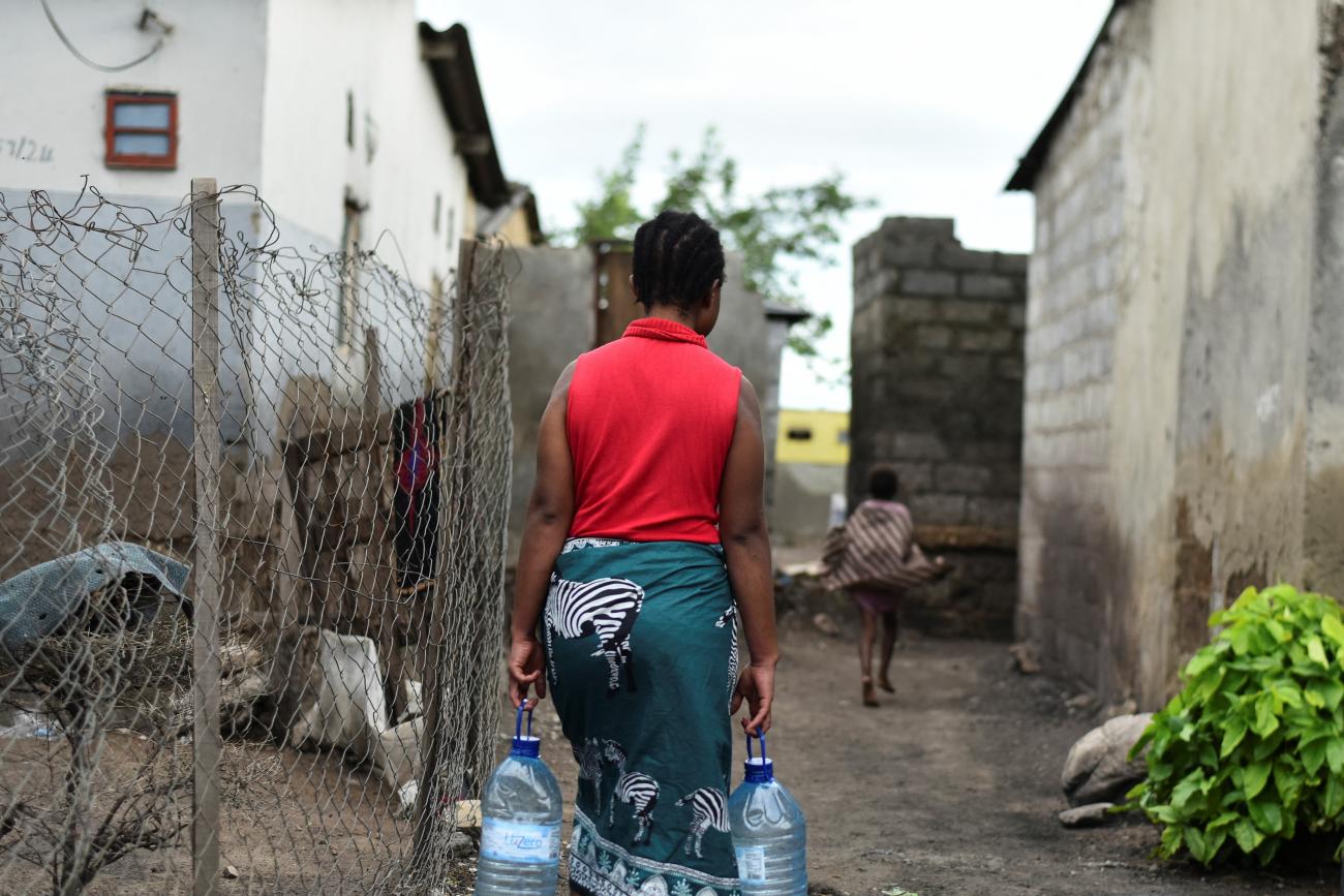 A woman carries bottles of water in a neighborhood affected by the cholera outbreak.