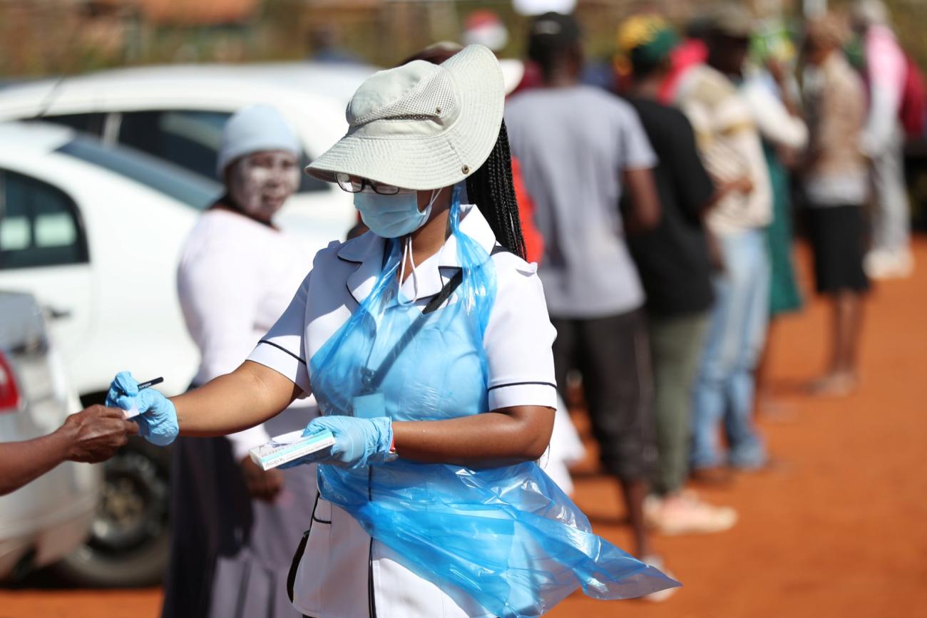 A member of medical staff attends to residents as they queue during screening and testing campaign aimed to combat the spread of COVID-19, in Lenasia, South Africa, on April 21, 2020.