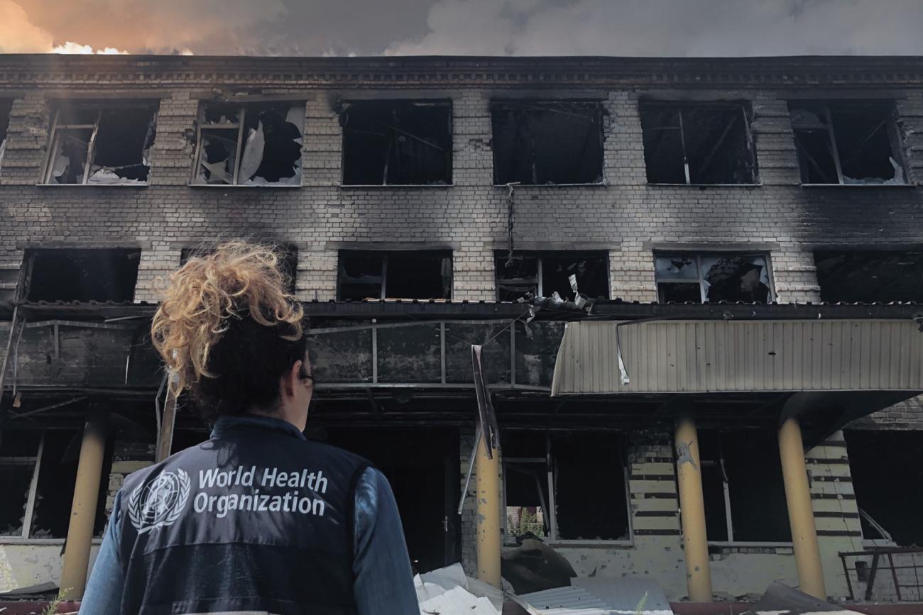 Member of a World Health Organization team is looking at destroyed school.