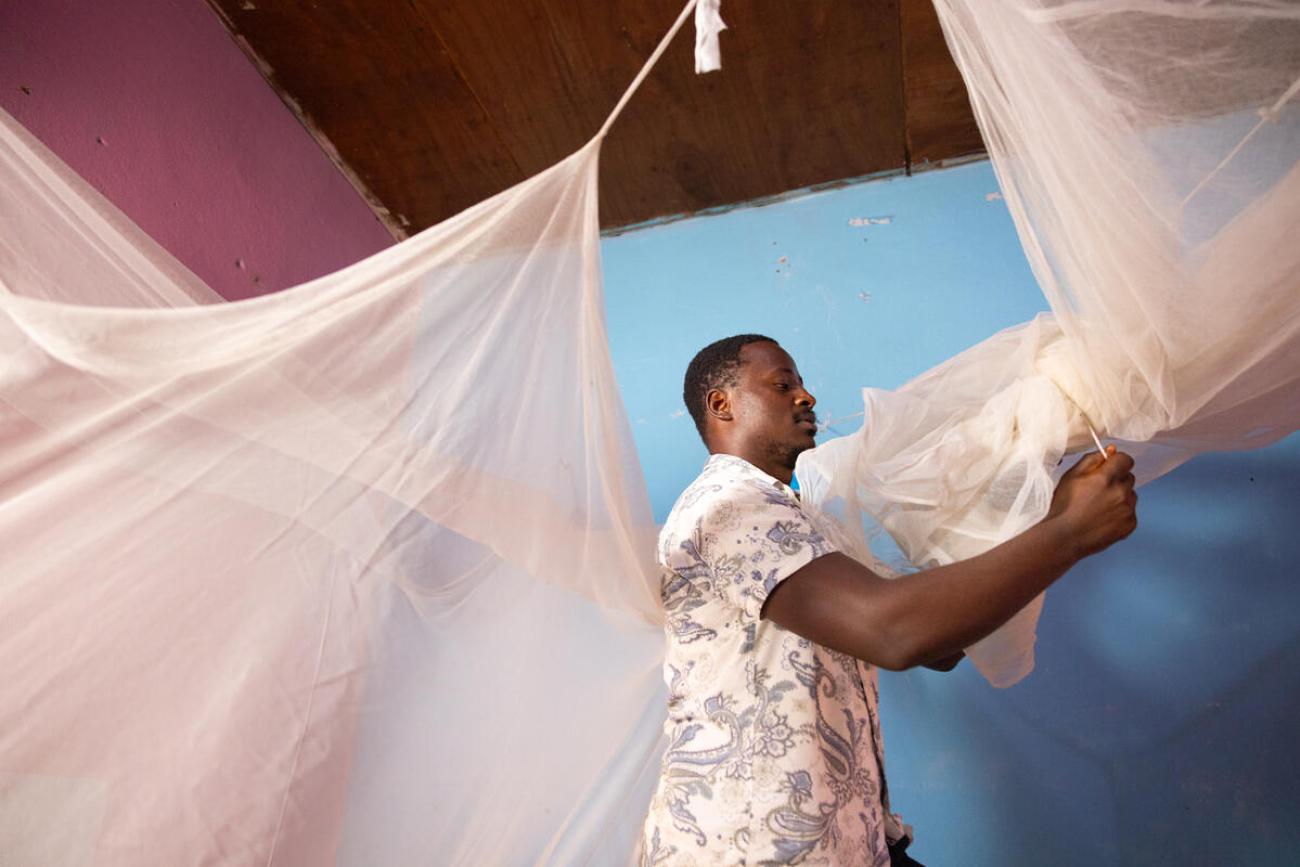 Tomnjong, a father of two, assembles a dual AI insecticide-treated mosquito net in his home.